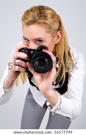 Young blond woman holding camera in studio