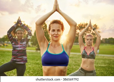 Young blond woman leading a yoga class at sunset in nature park  - Powered by Shutterstock