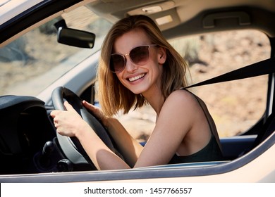 Young blond woman on road trip, smiling