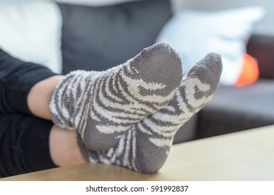 Young Blond Woman Relaxing With Feet Up On Table Wearing Socks, Focus On Foreground