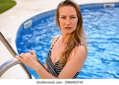 Young Blond Woman Swimming In The Swimming Pool At The Hotel Spa Outdoors In The Garden