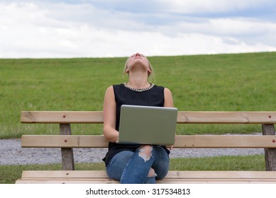 Young blond woman takes a short break as she sits on a park bench outdoors