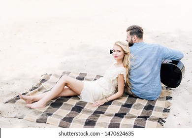 Young Blonde Barefoot Woman Leaning On Boyfriend With Acoustic Guitar At Beach