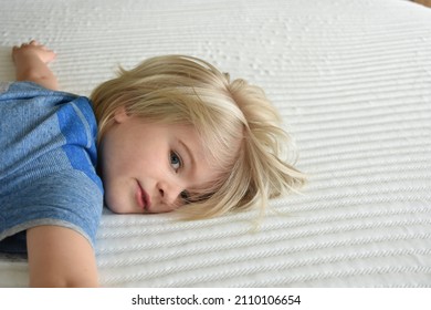 Young Blonde Boy Resting On A Bed Mattress