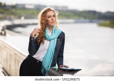 Young Blonde Business Woman With Long Curly Hairs Leaning On Parapet Stylish Fashion Model In Denim Jacket And Light Blue Scarf