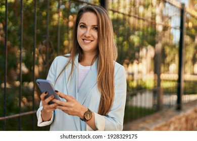 Young blonde businesswoman smiling happy using smartphone at the city. - Shutterstock ID 1928329175