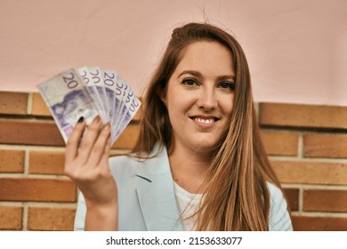 Young Blonde Businesswoman Smiling Happy Holding Sweden Krona Banknotes At The City.