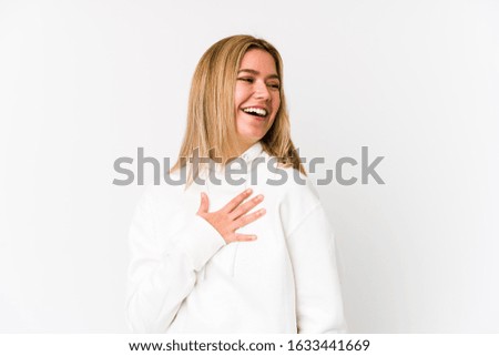 Young blonde caucasian woman isolated laughs out loudly keeping hand on chest.