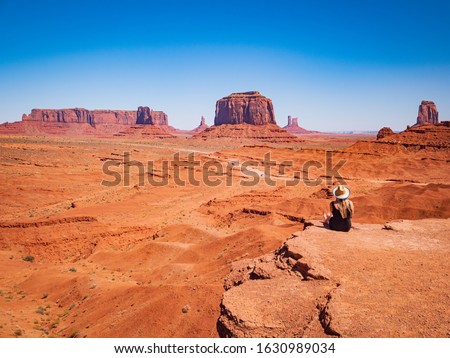Young blonde girl admires panorama from John Ford Point in Oljato Monument Valley, region of Colorado Plateau characterized by cluster of vast sandstone buttes, Arizona Utah border