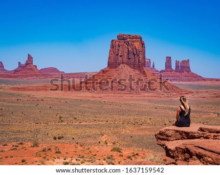 Young blonde girl admires panorama from Artist's Point in Oljato Monument Valley, region of Colorado Plateau characterized by cluster of vast sandstone buttes, Arizona Utah border.