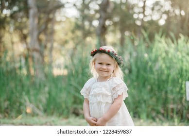 Young Blonde Girl Celebrating Australian Summer Christmas Outdoors Wearing White And Red Festive Colours And A Holly Berry Wreath Flower Crown