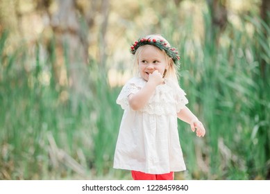 Young Blonde Girl Celebrating Australian Summer Christmas Outdoors Wearing White And Red Festive Colours And A Holly Berry Wreath Flower Crown