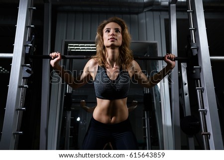 Young blonde girl is engaged with a barbell in the gym