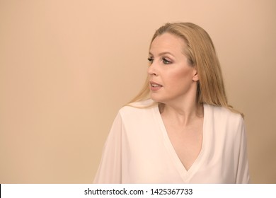 
Young Blonde Girl In Front Of Peachy Background. Looking At Her Side. Asking Myself What Is Happening. Banner With Copy Space.