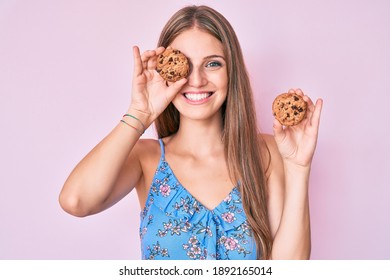 Young blonde girl holding cookie smiling with a happy and cool smile on face. showing teeth. 