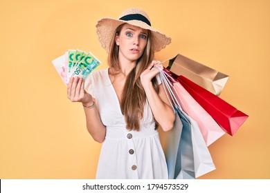 Young Blonde Girl Holding Shopping Bags And Israeli Shekels Clueless And Confused Expression. Doubt Concept. 