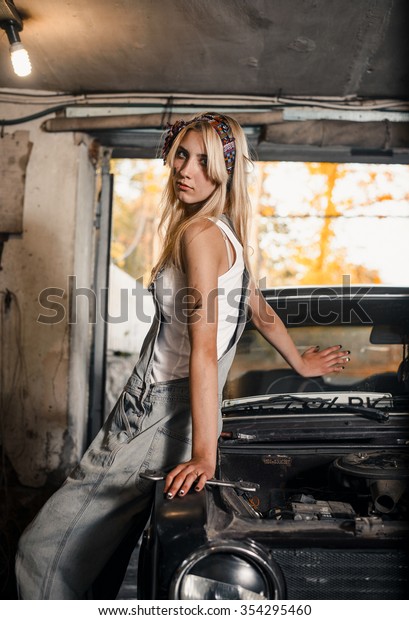 young blonde\
girl with long hair is an auto mechanic in the garage with a lot of\
tools on the shelves holding\
wrenches