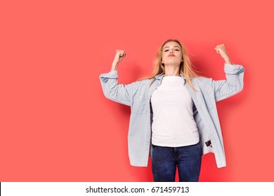 Young blonde girl shows her strength on red background. Picture including copy space for text