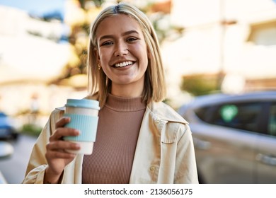 Young blonde girl smiling happy drinking take away coffee at the city.