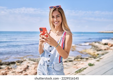 Young blonde girl smiling happy using smartphone at the beach. - Powered by Shutterstock
