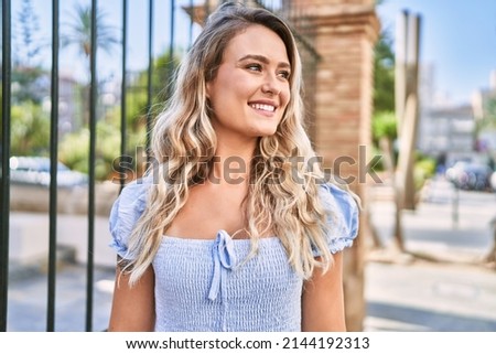 Young blonde girl smiling happy standing at the city