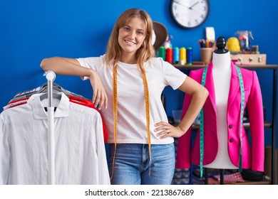 Young Blonde Girl Tailor Smiling Confident Leaning On Clothes Rack At Sewing Studio