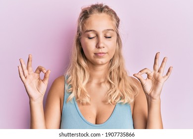 Young blonde girl wearing casual clothes relax and smiling with eyes closed doing meditation gesture with fingers. yoga concept. 