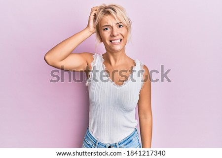 Young blonde girl wearing casual clothes confuse and wonder about question. uncertain with doubt, thinking with hand on head. pensive concept. 