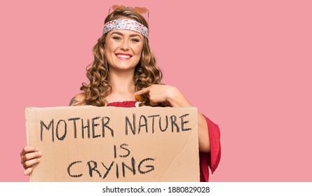 Young Blonde Girl Wearing Hippie Style Holding Mother Nature Is Crying Protest Cardboard Banner Pointing Finger To One Self Smiling Happy And Proud 