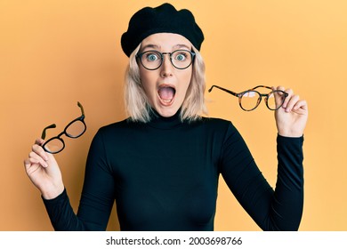 Young blonde girl wearing many glass over face celebrating crazy and amazed for success with open eyes screaming excited. 
