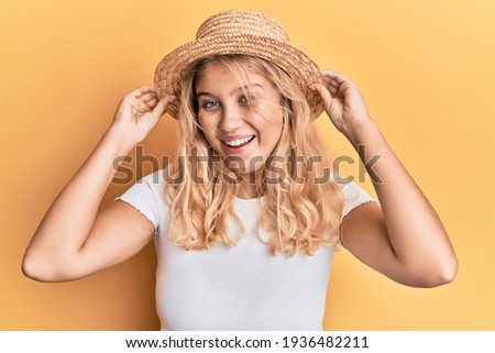 Young blonde girl wearing summer hat celebrating crazy and amazed for success with open eyes screaming excited. 
