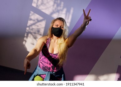 Young Blonde Girl Zumba Trainer Wears Black Mask During Pandemic.