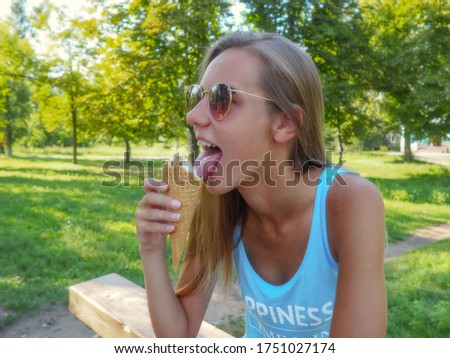Young blonde hipster girl eating a delicious ice cream in summer hot weather in sunglasses