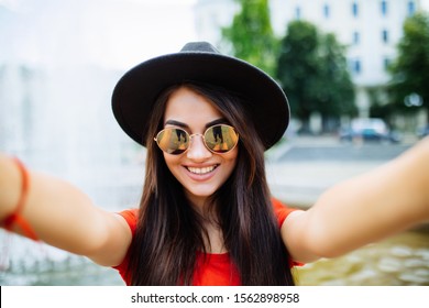 Young Blonde Hipster Woman, Making Selfie, Showing Tongue, Funny Face, Posing At Countryside At Autumn Day, Stylish Hat And Clear Sunglasses.