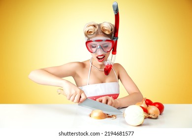 Young blonde housewife chopping onion in diving mask to protect her eyes. Retro classic 50s style photoshoot.