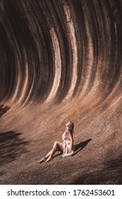 Young blonde lady, a tourists, is sun bathing at the Wave Rock- Western Australian tourist destination- a rock formation resembling a wave in Hyden. Australia. 