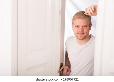 A Young Blonde Man Coming Home Passing Through The Door.