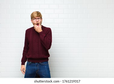 young blonde man and mouth   eyes wide open   hand chin  feeling unpleasantly shocked  saying what wow agaist vintage tiles wall