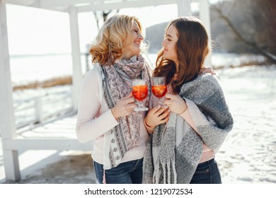 young blonde mom with her grown up daughter in the spring park with mulledwine