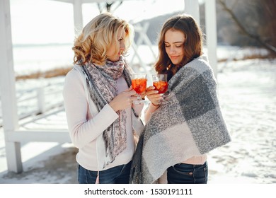 young blonde mom with her grown up daughter in the spring park with mulledwine