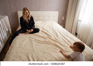 Young blonde mother having quality time with her baby boy son at family home flat - Wearing black budoir dress costume sleeping gown