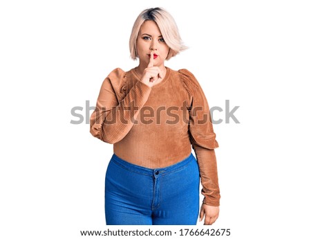 Young blonde plus size woman wearing casual sweater asking to be quiet with finger on lips. silence and secret concept. 