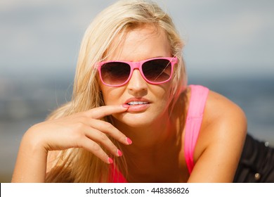 Young Blonde Pretty Girl On Beach With Finger Touching Lips Woman Wearing Sunglasses Have Active Time In Summer. Summertime Concept.