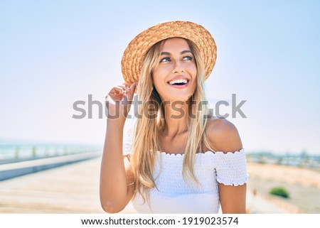 Young blonde tourist girl smiling happy looking to the side walking at the promenade.