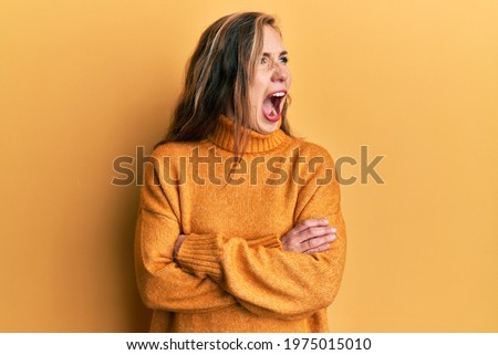 Young blonde woman with arms crossed gesture angry and mad screaming frustrated and furious, shouting with anger. rage and aggressive concept. 