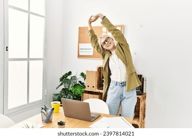 Young blonde woman business worker stretching back standing at office - Powered by Shutterstock