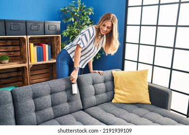 Young Blonde Woman Cleaning Sofa Using Pet Hair Roller At Home