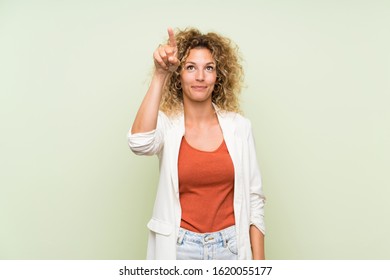 Young blonde woman with curly hair over isolated green background touching on transparent screen - Powered by Shutterstock