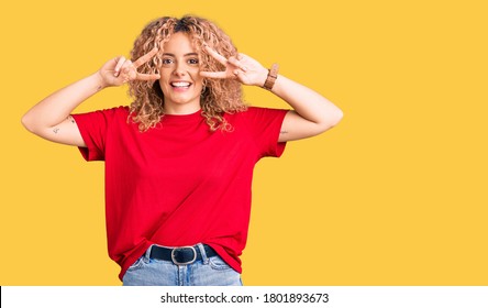 Young Blonde Woman With Curly Hair Wearing Casual Red Tshirt Doing Peace Symbol With Fingers Over Face, Smiling Cheerful Showing Victory 