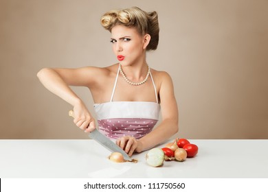 Young blonde woman cutting onion in kitchen
